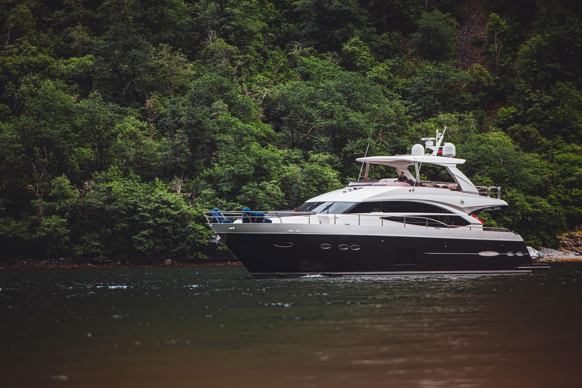 The Princess 72 under way along a wooded fjord shoreline